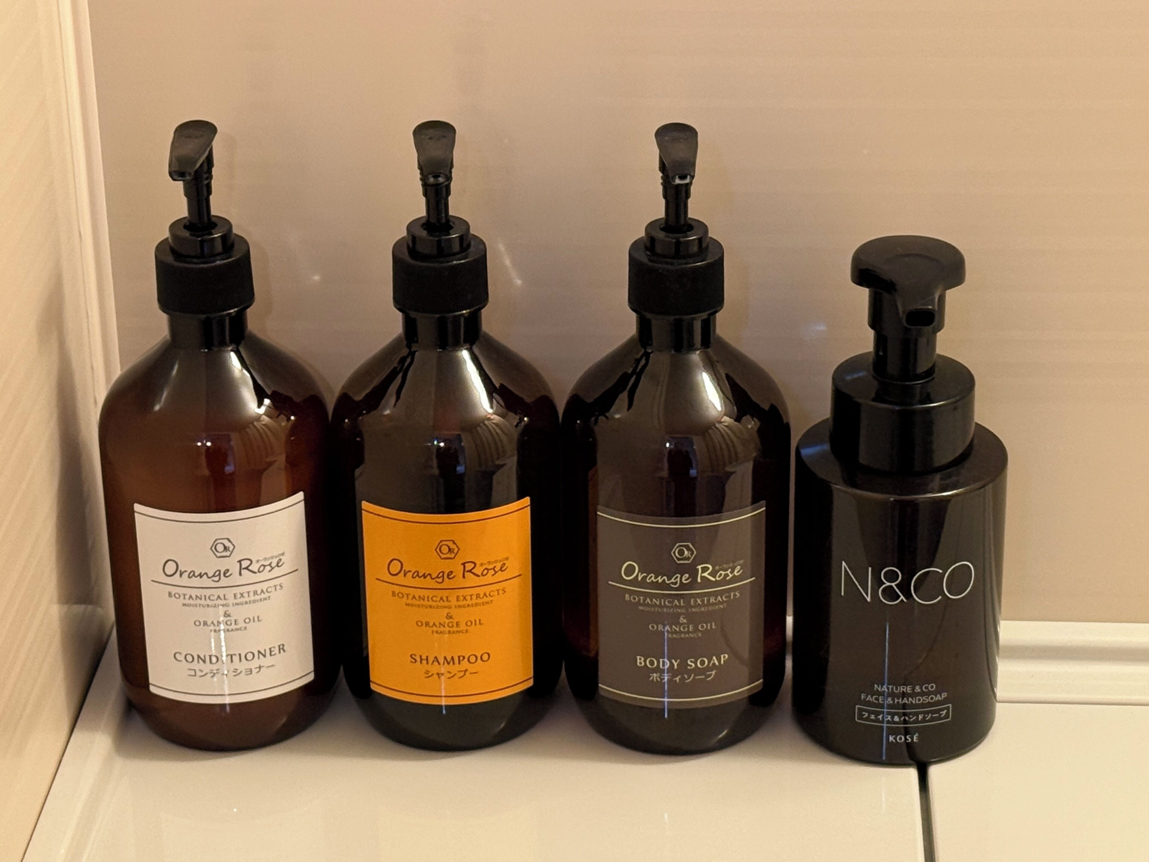Four bottles of Orange Rose products: conditioner, shampoo, body soap, and N&CO face & hand soap.