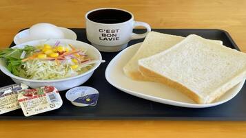 Ein Tablett mit einem Sandwich, einer Tasse, einem Salat und zwei Marmelapäckchen.