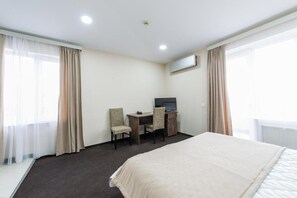 A hotel room with a bed, a desk with a chair, a television, and curtains. - Check-in TERRACE Hotel (Baku)