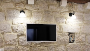 A television mounted on a stone wall with two wall-mounted lamps.