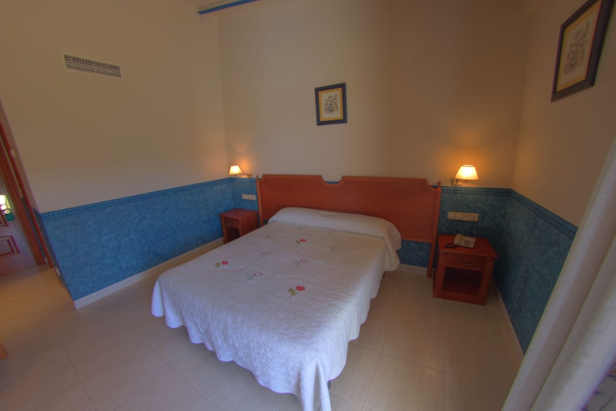 A bedroom with a single bed, two bedside tables, and a nightstand with a lamp.