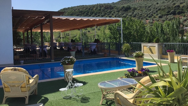 A poolside area with a covered seating area, outdoor furniture, and a view of the surrounding landscape. - Hotel Avenida (Beas de Segura)