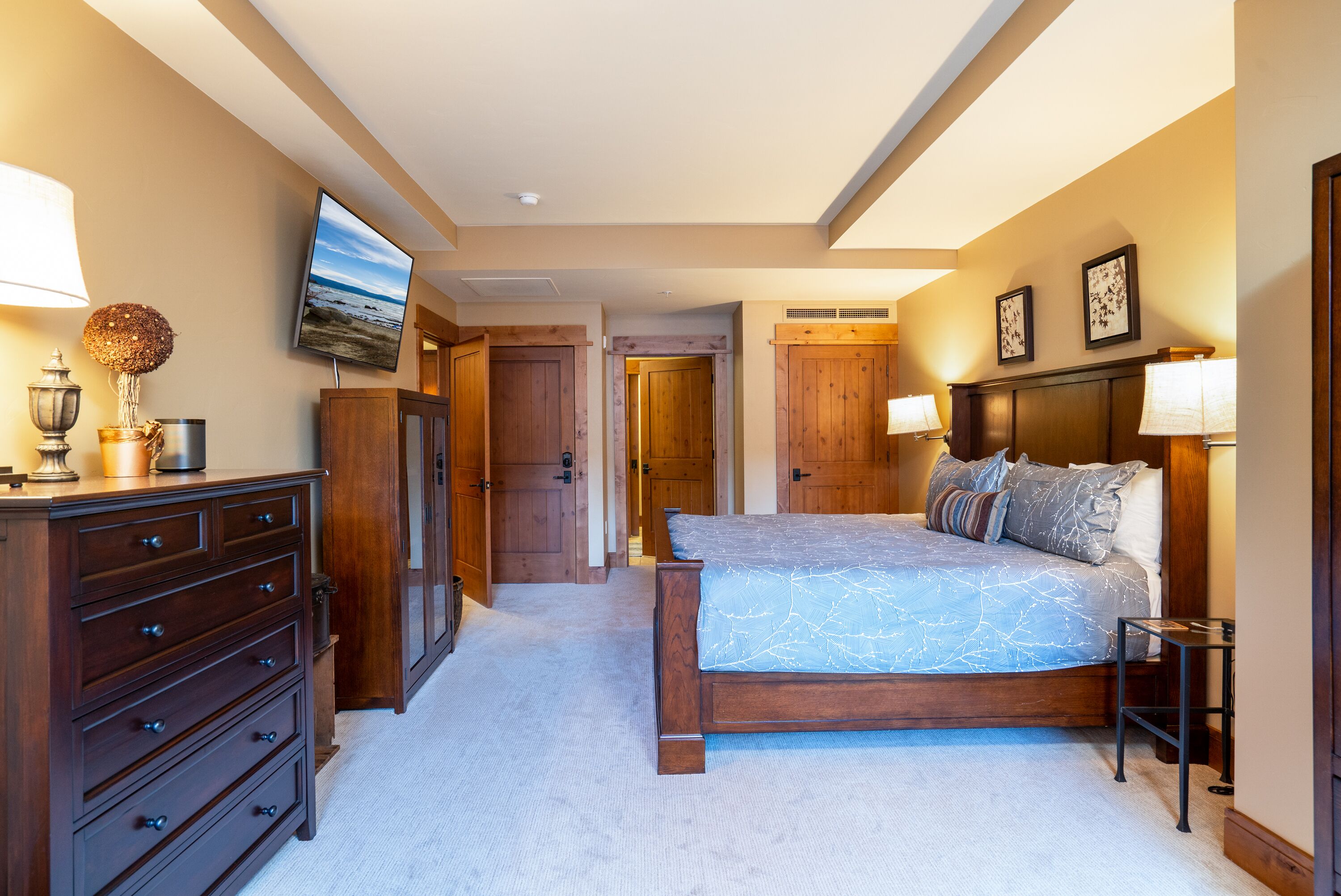 Un dormitorio con cama, cómoda y televisor en la pared.