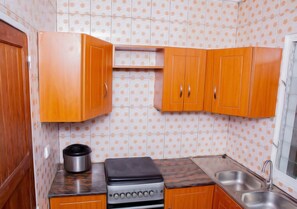 Cozinha compacta com armários de madeira, fogão, pia e painel de fundo com bolinhas.