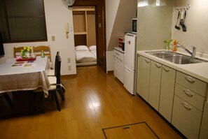 Eine kleine Küche mit Spüle, Kühlschrank und Holzboden.