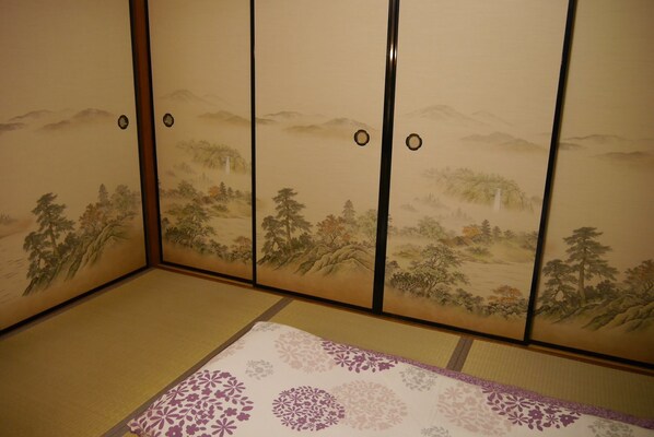 A traditional Japanese room with tatami flooring and shoji screens depicting nature scenes.