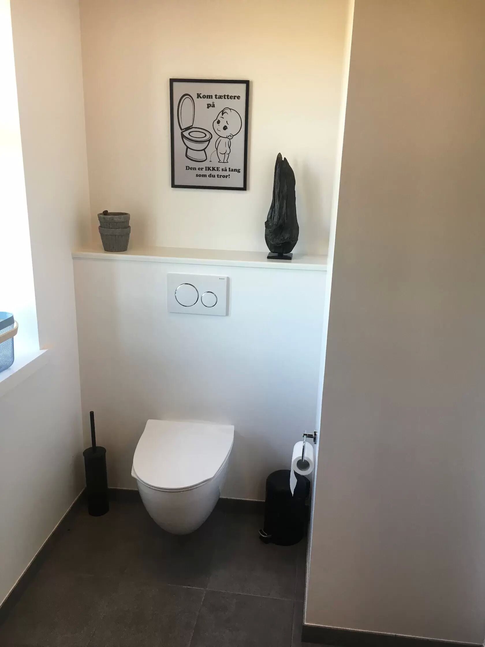 A small, modern bathroom with a toilet, bidet, and a wall-mounted toilet paper holder.