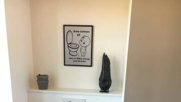 Un baño pequeño y moderno con inodoro, bidé y un dispensador de papel higiénico en la pared.