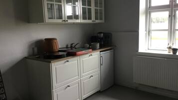 Una cocina con armarios blancos, cafetera y ventana con vistas.