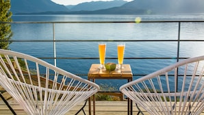 A terrace with two wicker chairs, a wooden table, and two glasses of orange juice. - Correntoso TownHouses (Villa La Angostura)