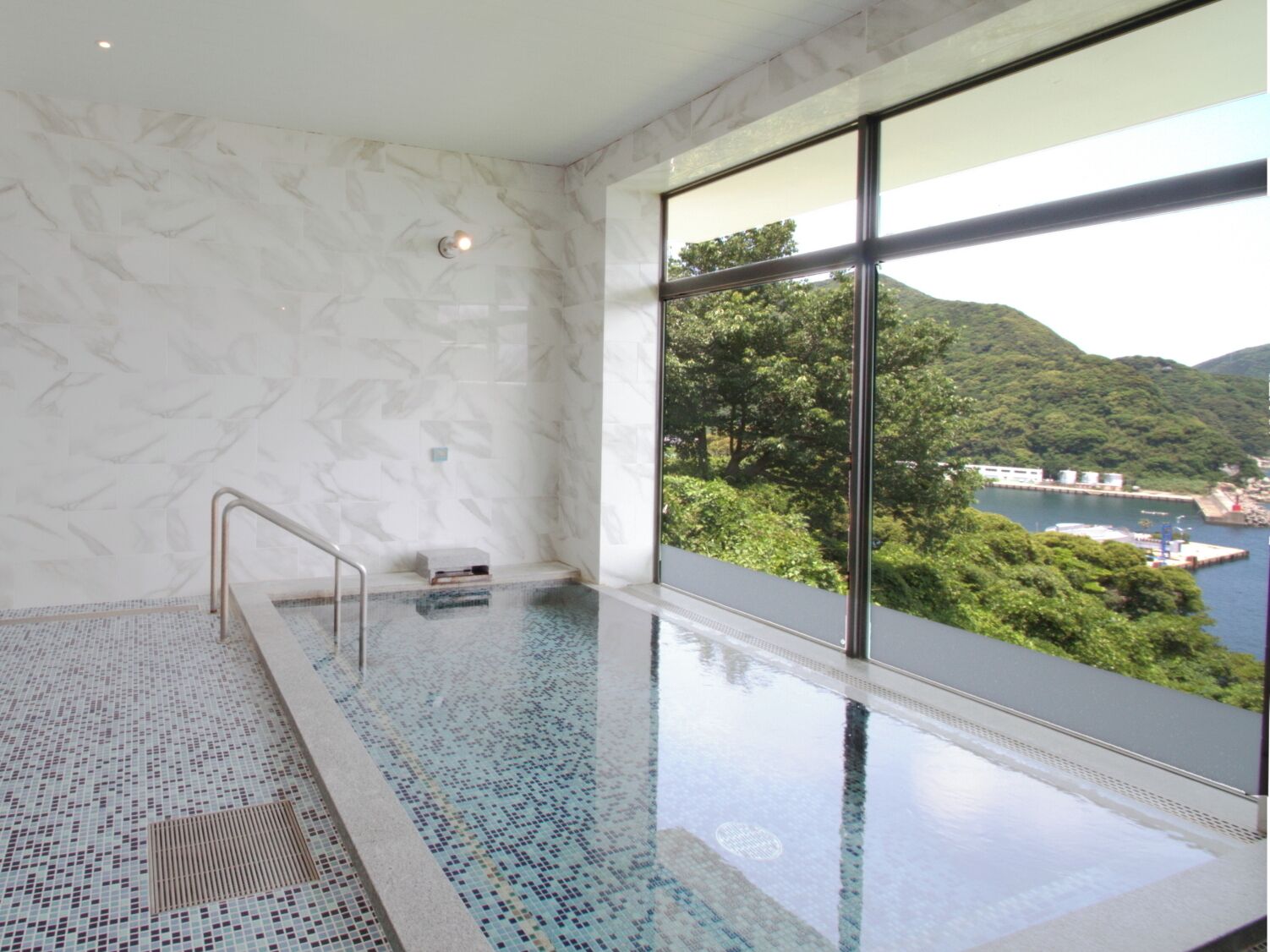 Una piscina coperta moderna con una vista chiara su un paesaggio montuoso attraverso ampie finestre.