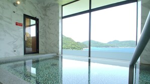 Ein Hallenbad mit Blick auf eine gebirgige Landschaft und ein Gewässer.