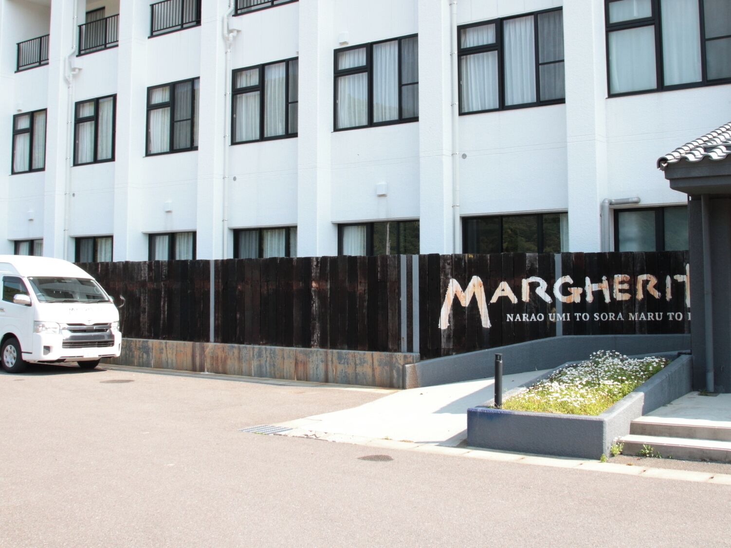 A white building with a black fence and a sign that reads "MARSHERIT".