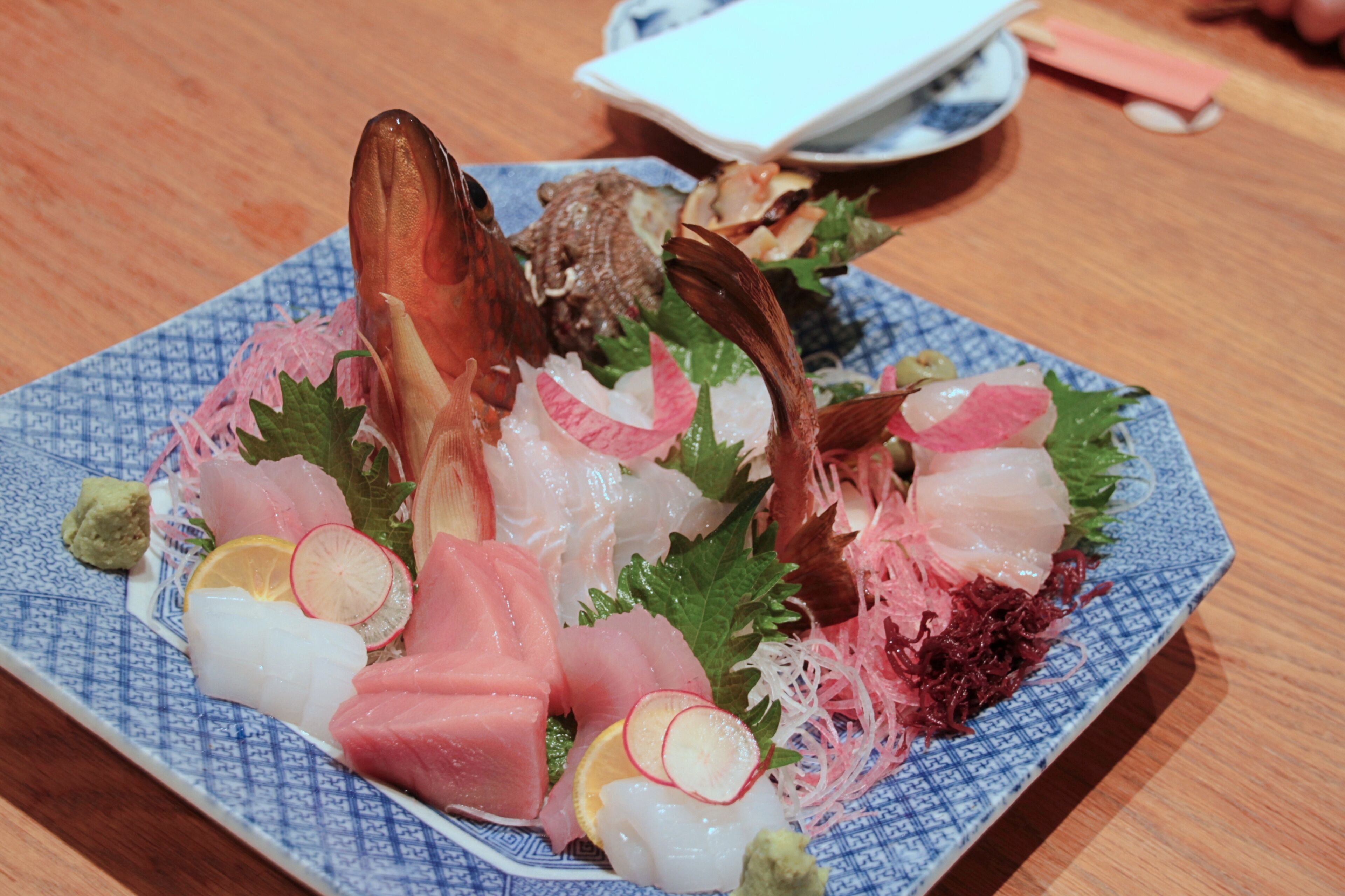 A plate of sashimi with various fish and garnishes.
