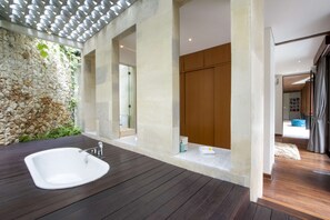 A modern bathroom with a stone wall, a wooden floor, and a large sink.