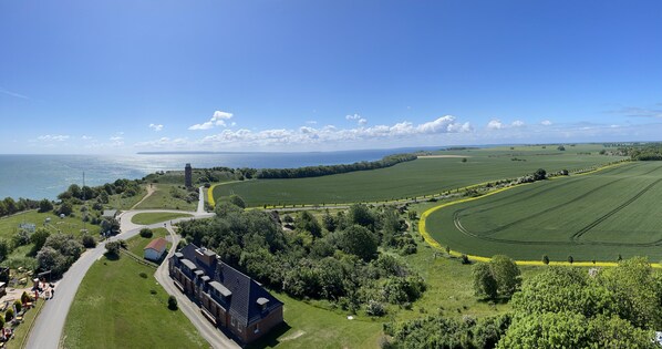A large building with multiple windows and a flat roof, surrounded by green fields and a road.