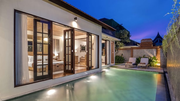 Ein modernes Haus mit Swimmingpool, großen Schiebeglasfenstern und einer Terrassenanlage mit Liegestühlen.