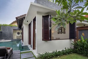 A modern villa with a swimming pool, a covered outdoor area, and lush greenery.