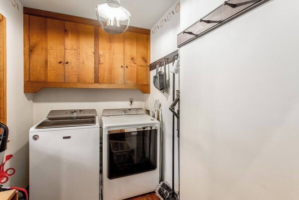 A compact kitchen with wooden cabinets, a washing machine, and a dryer.