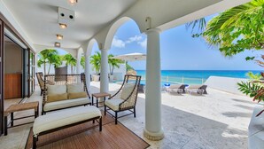 A covered outdoor seating area with a view of the ocean, featuring wicker furniture and a bamboo mat. - Dream Villa Shore Point 553 (Lowlands)
