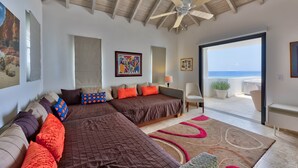 A spacious bedroom with a large bed, a ceiling fan, and a view of the ocean through a sliding glass door. - Dream Villa Shore Point 553 (Lowlands)
