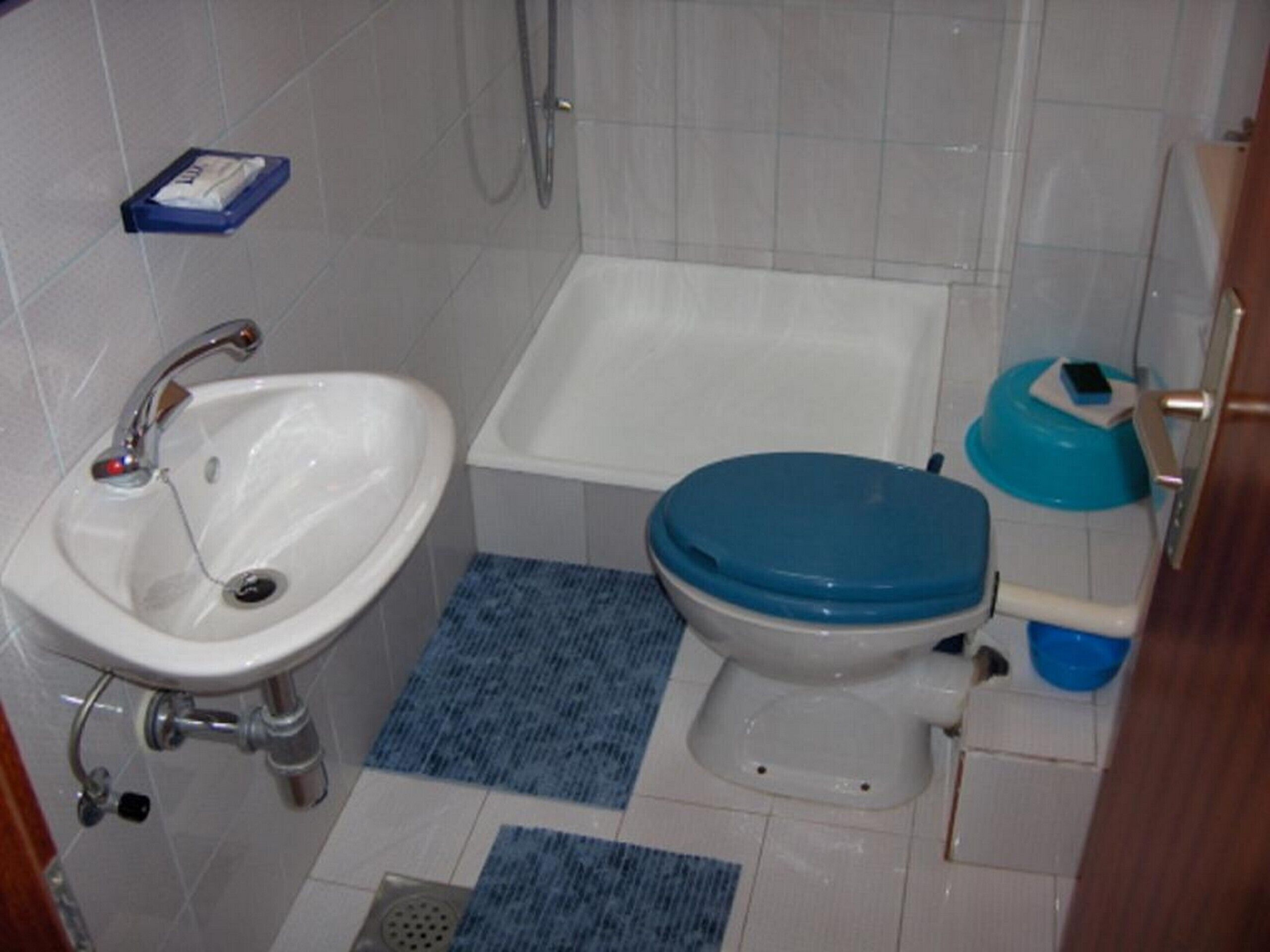 A bathroom with a white sink, a toilet with a blue lid, and a bathtub.