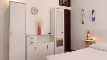 Une chambre à coucher comprenant un lit, une armoire, un miroir, une table de chevet avec une lampe et une horloge murale.