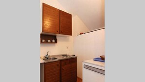 A compact kitchen with wooden cabinets, a sink, and a dishwasher. - Apartments Nadia (Bol)