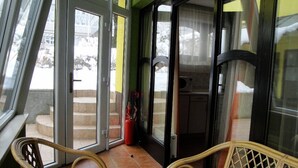 A room with a glass door leading outside, a wicker chair, and a red fire extinguisher near the door.