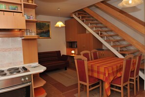 Une cuisine équipée d’une cuisinière, une table à manger avec des chaises, un canapé et un escalier.