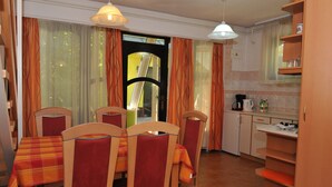 A dining area with a table set for four, chairs, a kitchen area with a coffee maker, and a view through a door.