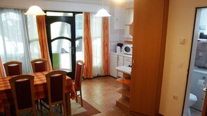 A dining area with a table and chairs, a kitchen with a microwave, and a view through a door.