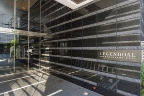 Enter through the glass door into LEGENDDOAL SHINSAIBASHI-EAST, a sleek building with a tile-paved ground.