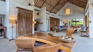 A spacious living area with a large wooden dining table, wicker chairs, and a sofa with blue cushions. - Bali Villa Near the Beach, 2056 (Seminyak)