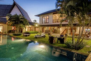 A modern house with a swimming pool, outdoor seating, and a well-maintained garden.