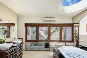 A modern bathroom with a large bathtub, a double sink vanity, and a large window with a view of a rocky landscape. - Beautiful Villa With Private Pool, Bali Villa 2017 (Seminyak)