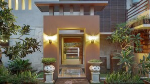 A modern house entrance with a central doorway, flanked by two wall-mounted lights, and surrounded by potted plants. - Beautiful Villa With Private Pool, Bali Villa 2017 (Seminyak)