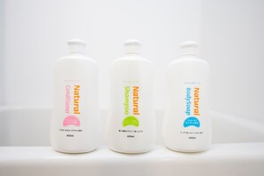 Three bottles of natural shampoo and conditioner on a white surface.