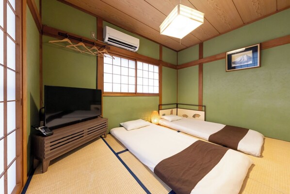 Une chambre avec deux lits, une télévision, une armoire et une fenêtre donnant sur un paysage agréable.