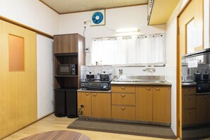 Une cuisine de taille réduite, équipée d’une cuisinière, d’un four à micro-ondes, d’un évier et de meubles de rangement en bois.