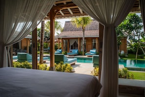 A bedroom with a view of a pool and outdoor seating.