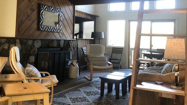 A spacious living room with a high ceiling, a fireplace, and a view of the outdoors through large windows. - Slopeside  at Hunter Mountain (Hunter)