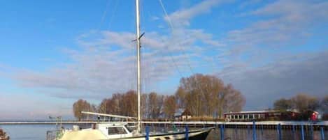 A docked sailboat at a marina with a clear sky and trees in the background.