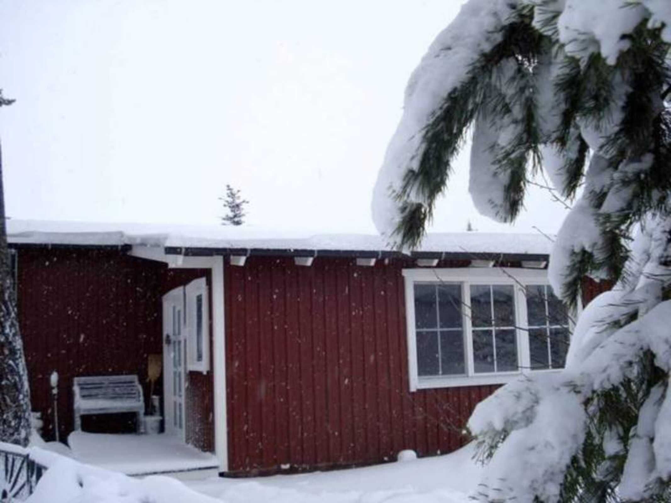 A red wooden building with a snow-covered roof and a visible door.