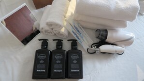 Un baño ordenado con una toalla blanca, un secador de pelo y tres botellas de artículos de aseo 'Vintage Style Classical'.