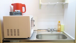 Una kitchenette compacta equipada con microondas, tostadora y un refrigerador pequeño.