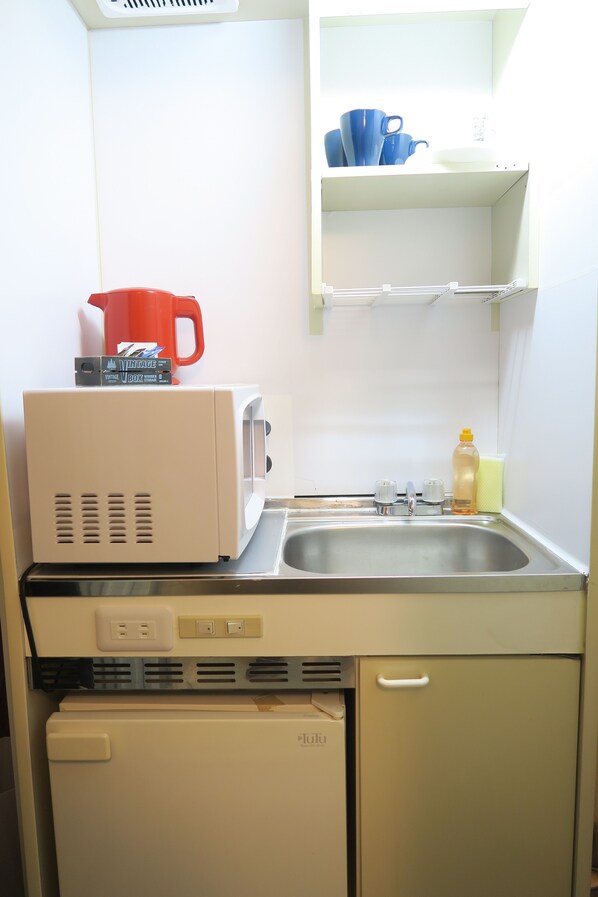 Una kitchenette compacta equipada con microondas, tostadora y un refrigerador pequeño.