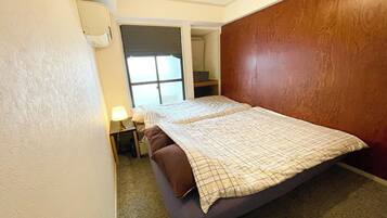 A bedroom with a bed, a nightstand, a lamp, and a window with blinds.
