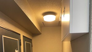 Un pasillo estrecho con dos puertas, una lámpara en el techo y una pared blanca.