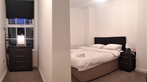 A bedroom with a bed, a dresser, and a nightstand. - Riverside 2 (Maidstone)